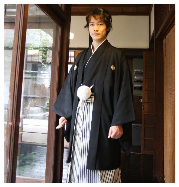 The Montsuki Haori Hakama is a traditional Japanese formal attire for men. The Montsuki Haori Hakama consists of a crested full-length garment called a nagagi, a pleated, divided skirt called a hakama, and a crested traditional half coat called a haori. The outfit is used in various ceremonial occasions such as weddings, funerals, grand sumo tournaments, and announcements of succession to a new, professional name. Traditional Japanese Wedding, Japanese Wedding Dress, Formal Attire For Men, Divided Skirt, Poet Shirt, Japanese Wedding, Wedding Dress Men, African People, Formal Attire