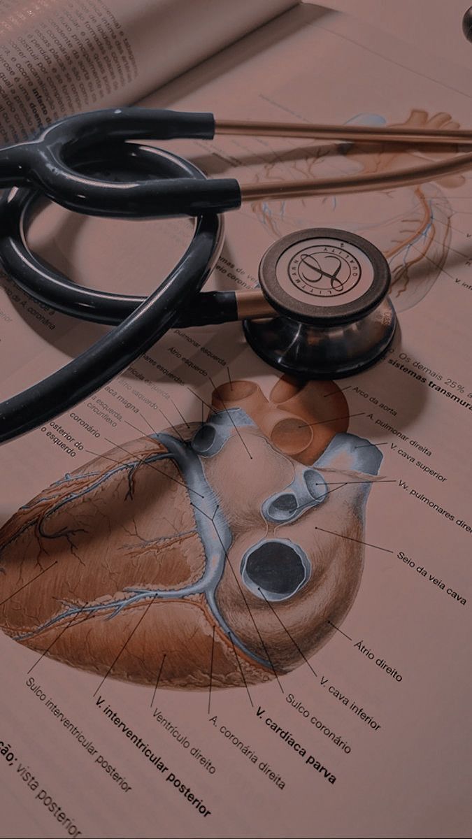 a stethoscope laying on top of a medical book with an image of the human body