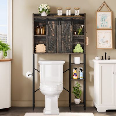 a white toilet sitting next to a wooden shelf filled with bathroom items on top of a hard wood floor