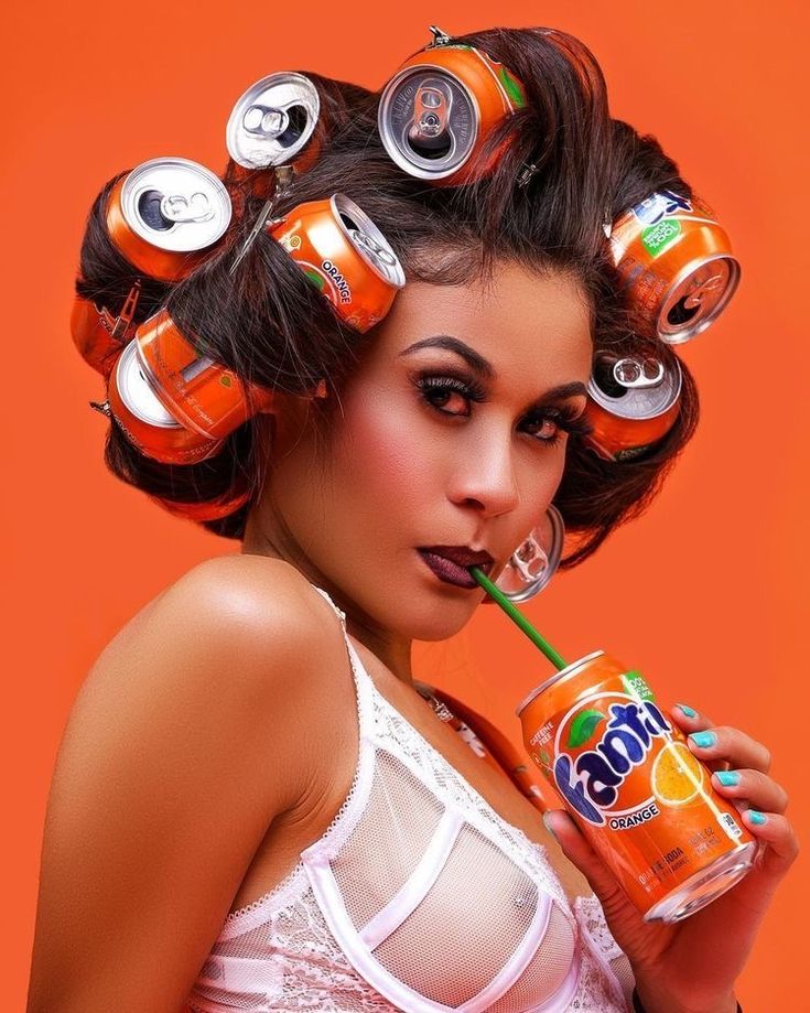 a woman with cans on her head drinking a drink and holding a straw in her mouth