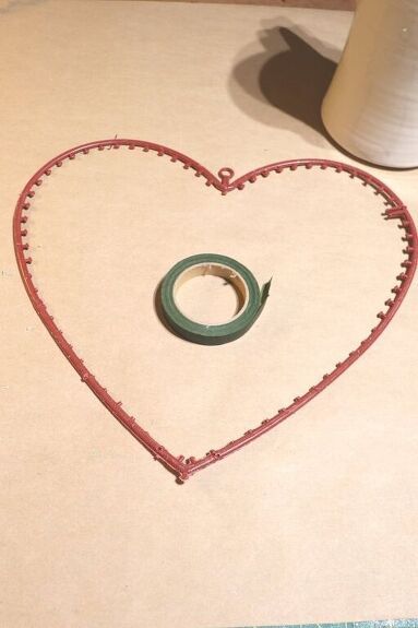 a heart shaped frame with a tape in the middle and a roll of toilet paper next to it