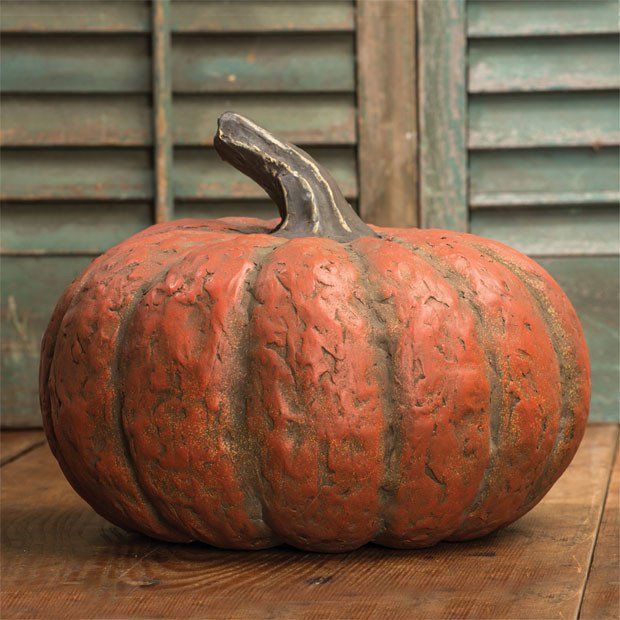 a large orange pumpkin sitting on top of a wooden table next to a green shuttered wall