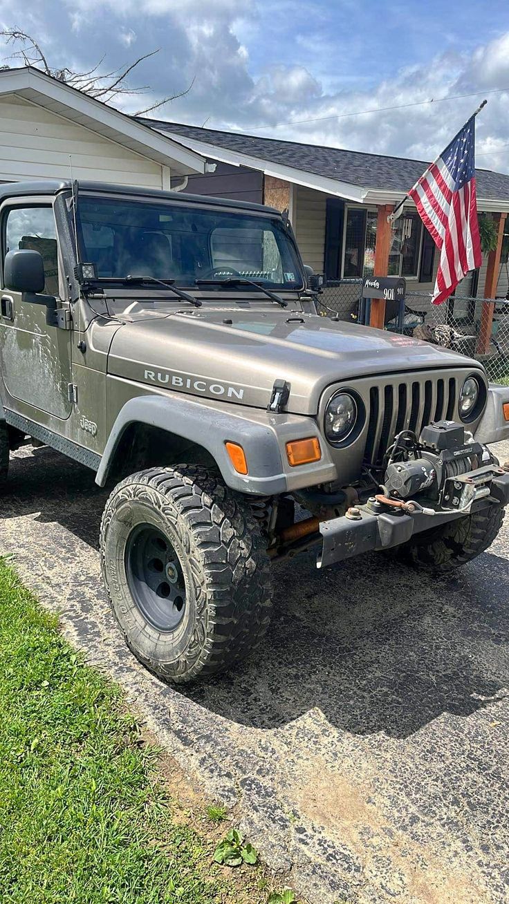 a jeep parked in front of a house with an american flag