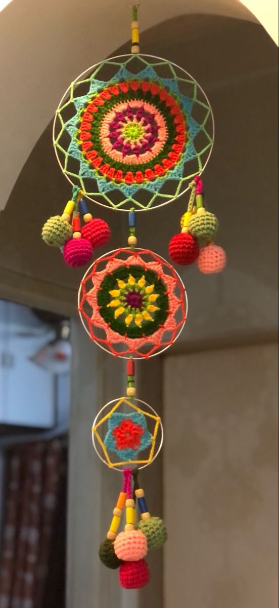 a multicolored crocheted dream catcher hanging from a ceiling in a room