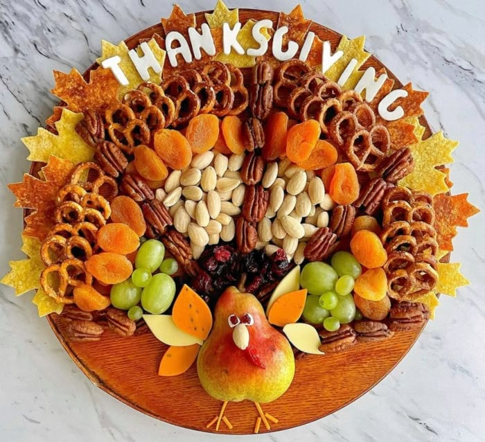 a thanksgiving turkey platter with nuts, grapes, and apples