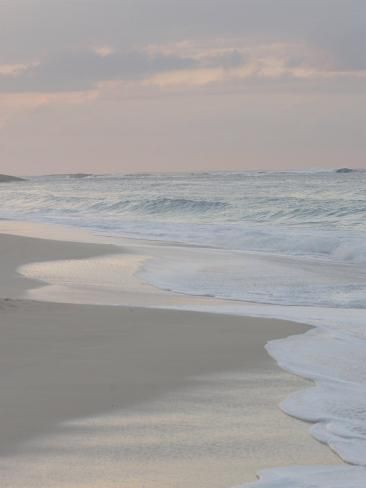 two people walking on the beach with surfboards