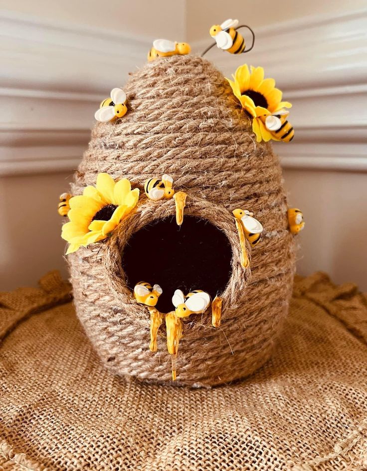 a birdhouse with sunflowers and bees on the inside is sitting on a burlap mat