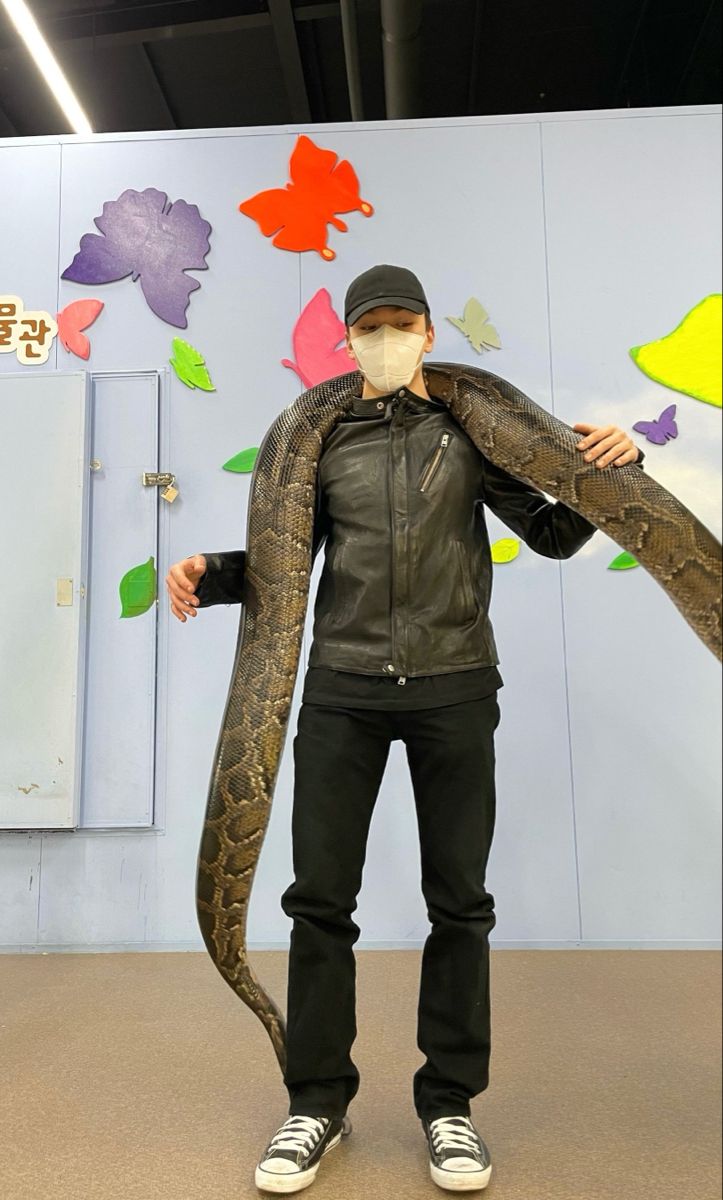 a man wearing a face mask holding a large snake