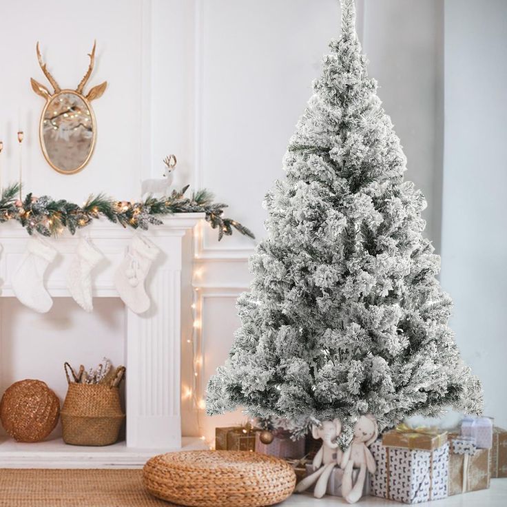 a white christmas tree sitting next to a fireplace