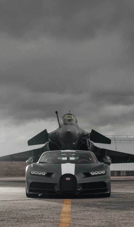 a black and white bugatti is parked in front of an airplane on the runway