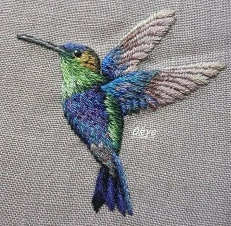 a colorful hummingbird sitting on top of a piece of cloth