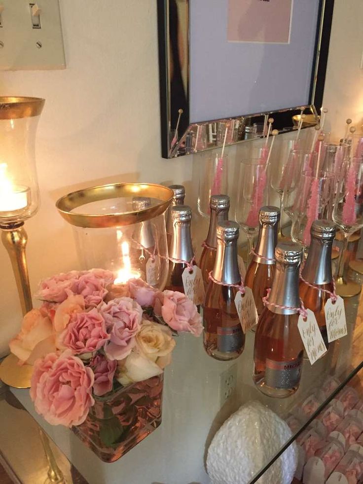 there are many bottles on the table with flowers and candles in front of each one