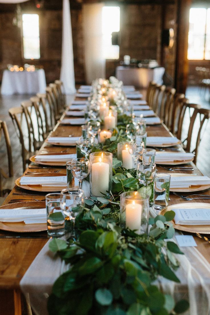 the long table is set with candles and greenery