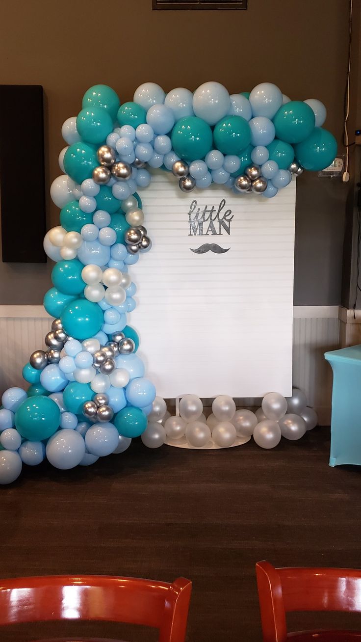 an arch made out of balloons with a mustache on the front and blue, white and silver balloons in the back