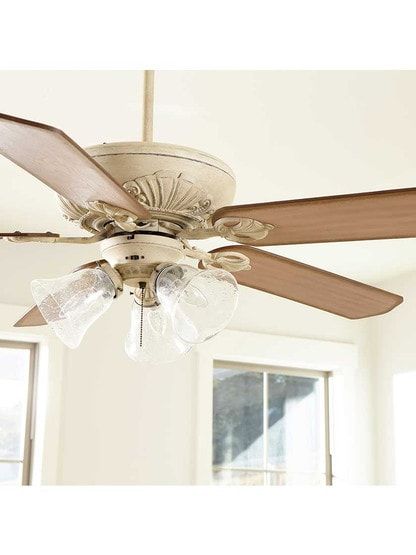 a ceiling fan with three glass shades on it's blades in a living room