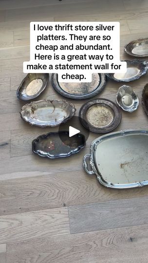 a pile of silver plates sitting on top of a wooden floor