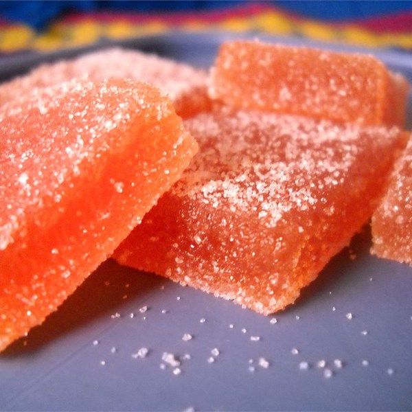 two pieces of orange gummy bears on a plate with sprinkles around them