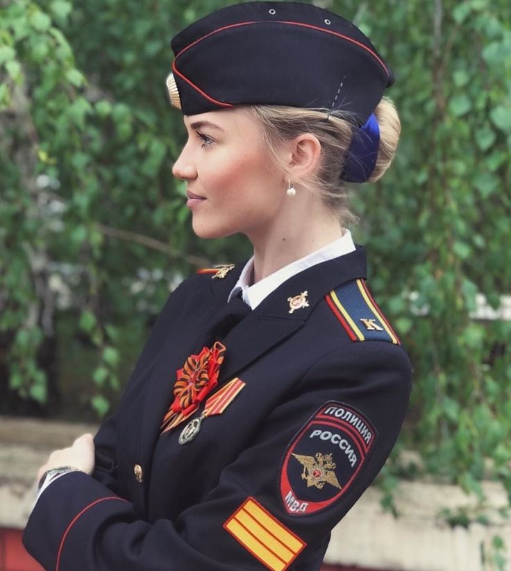 a woman in uniform is standing with her arms crossed and looking off to the side