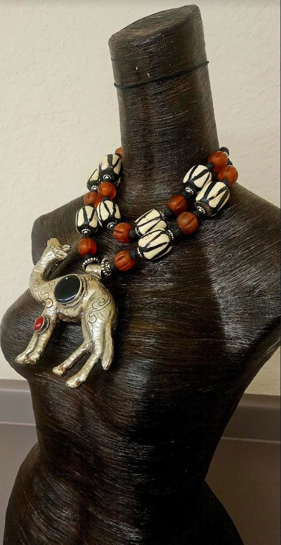 This rare and scarce tribal statement necklace is new and unworn from my private collection. It features a very hard to find Tibetan Repousse Camel pendant with inlaid black onyx and red carnelian. I remain uncertain about the small gold metal spor at the 11 o'clock position in the onyx, but I purchased the stone like this. The camel is as ornate on the back as it is on the front, and measures a lightweight 5.25" x 5" (the camel is hollow). The adjustable double strand beaded necklace ranges fro Traditional Black Necklaces With Large Pendant, Traditional Black Necklace With Large Pendant, Bohemian Black Carved Necklace, Jewellery Shop Design, Turquoise Western, Red Carnelian, Chest Piece, Western Jewelry, Cuff Earrings