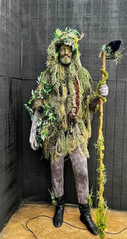 a man dressed in moss and holding a stick