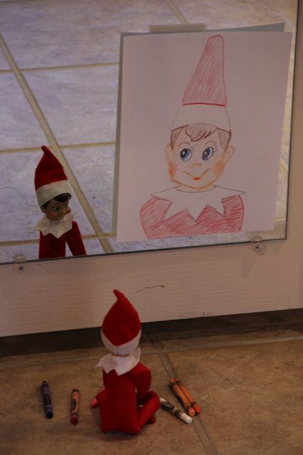 an elf sitting on the ground in front of a drawing and crayon pencils