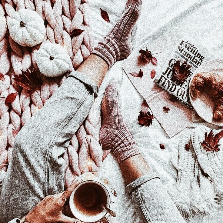 a person laying on a blanket with their feet up and holding a cup of coffee