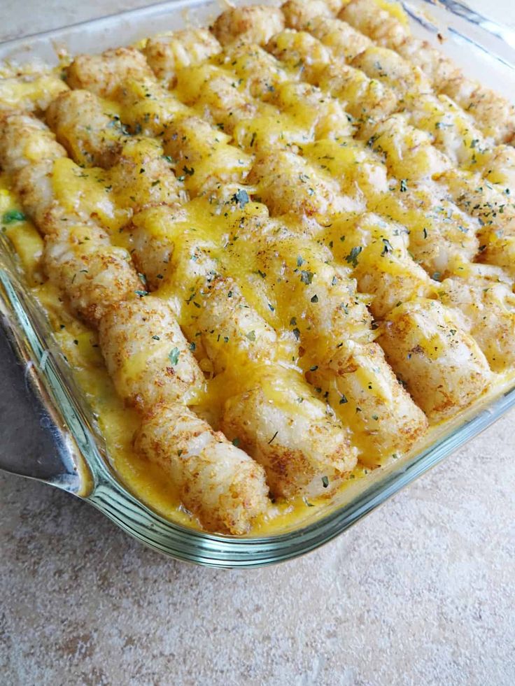 chicken tater tot casserole in a glass dish with cheese and herbs