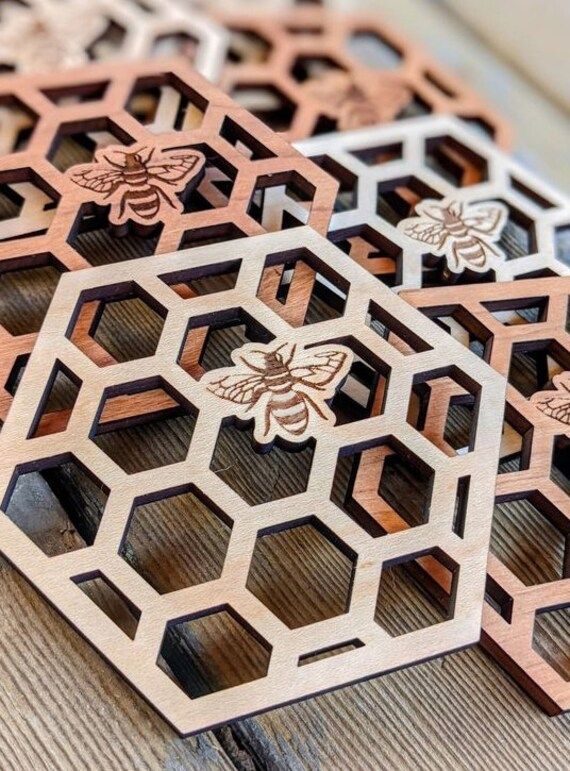 three wooden coasters that have bee designs on them