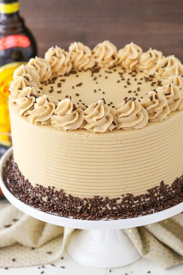 a cake with frosting and sprinkles sitting on a plate next to a bottle of beer