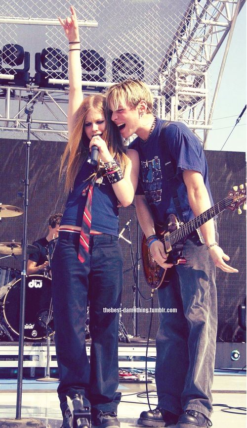 two young people standing on stage with guitars