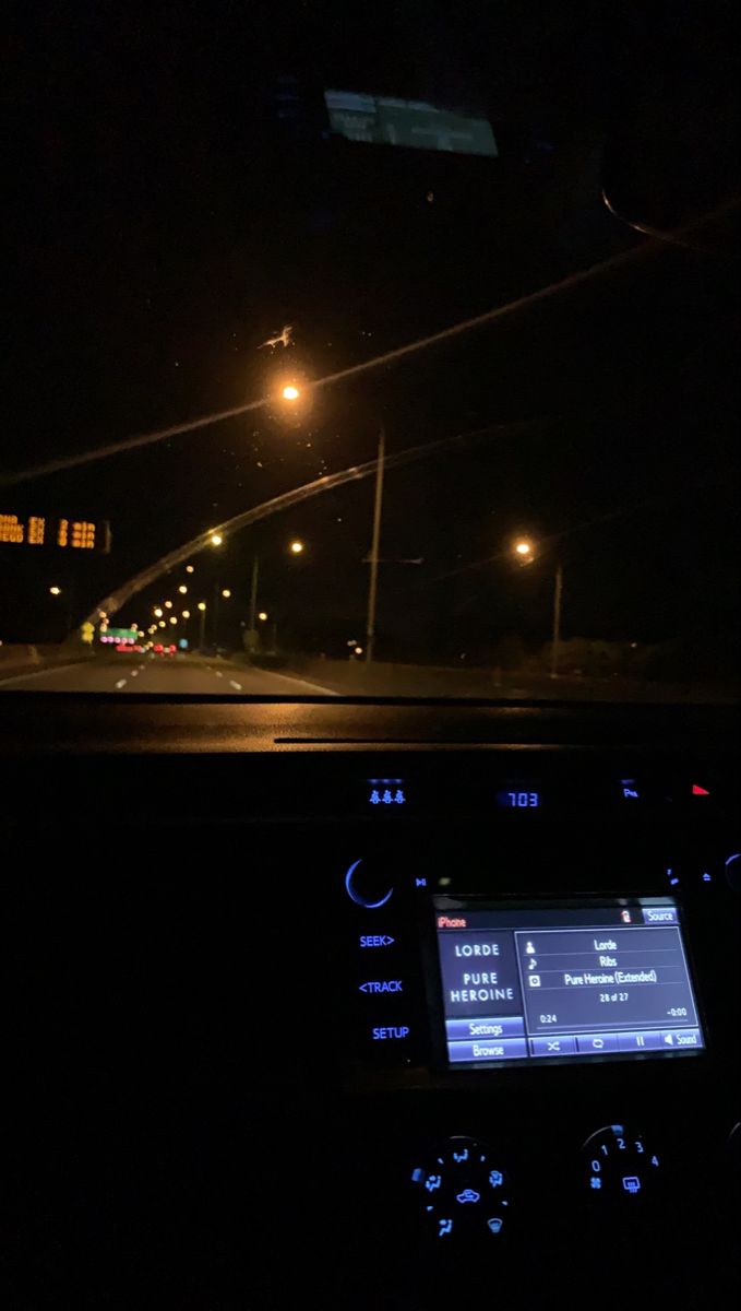 the dashboard of a car at night with its lights on and streetlights in the background