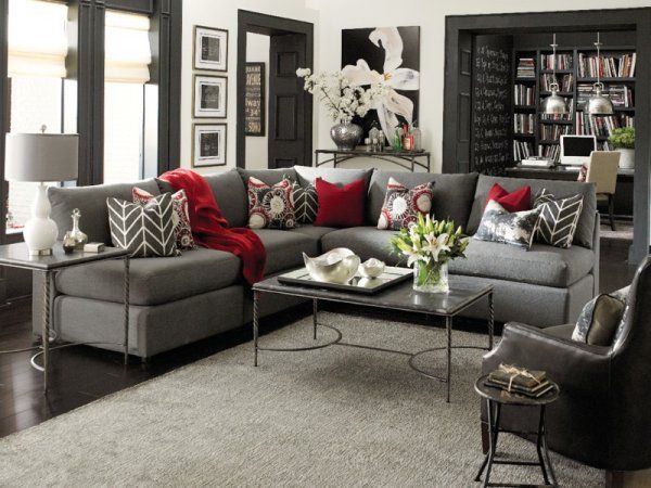 a living room with gray couches and red pillows