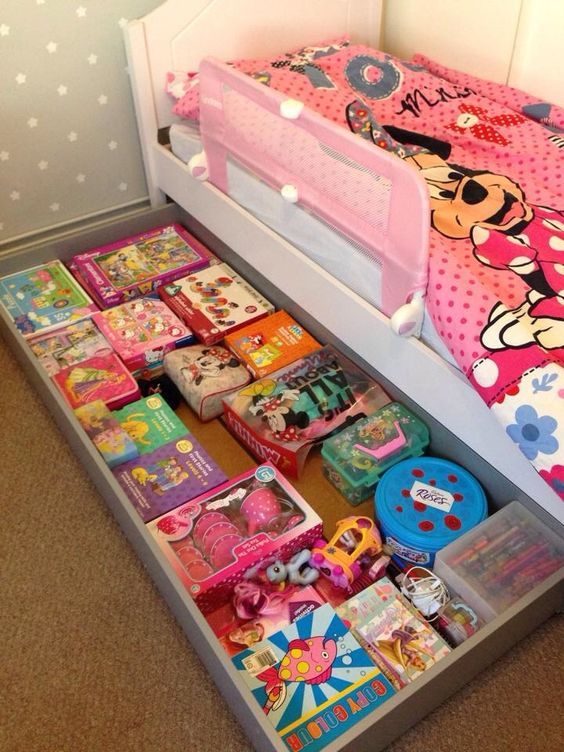 a child's bed with lots of toys on the bottom shelf and underneath it