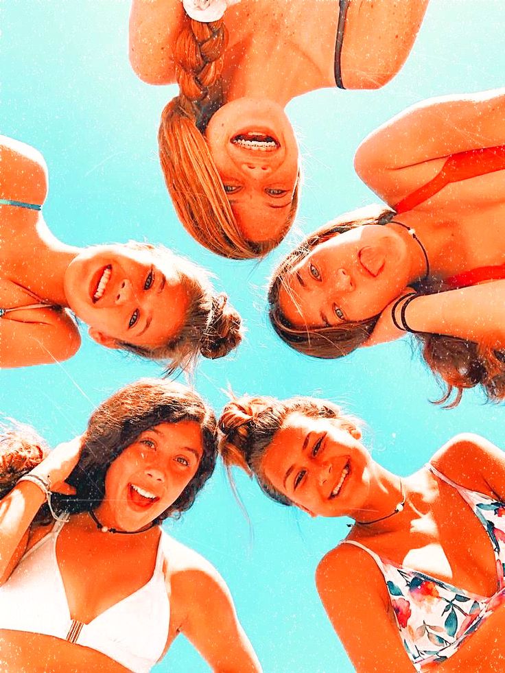 four women in bikinis are looking up at the camera with their heads tilted to the side