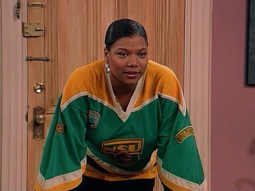 the young woman is wearing an ice hockey jersey and looking at the camera while standing in front of a door