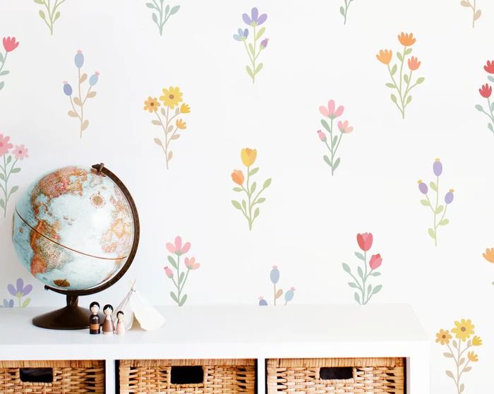 a wall with flowers painted on it next to two baskets and a globe in front of the wall