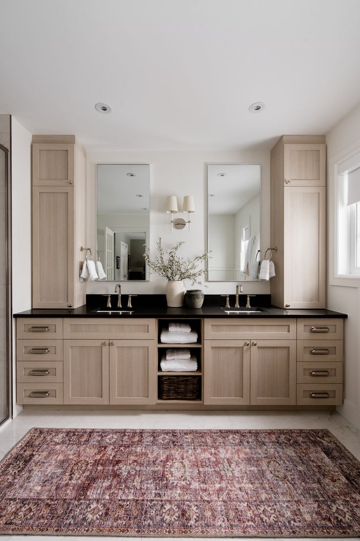 a large bathroom with two sinks, mirrors and rug on the floor in front of it