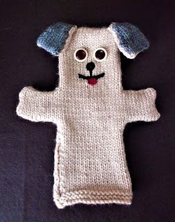 a knitted dog toy laying on top of a black surface with eyes and ears