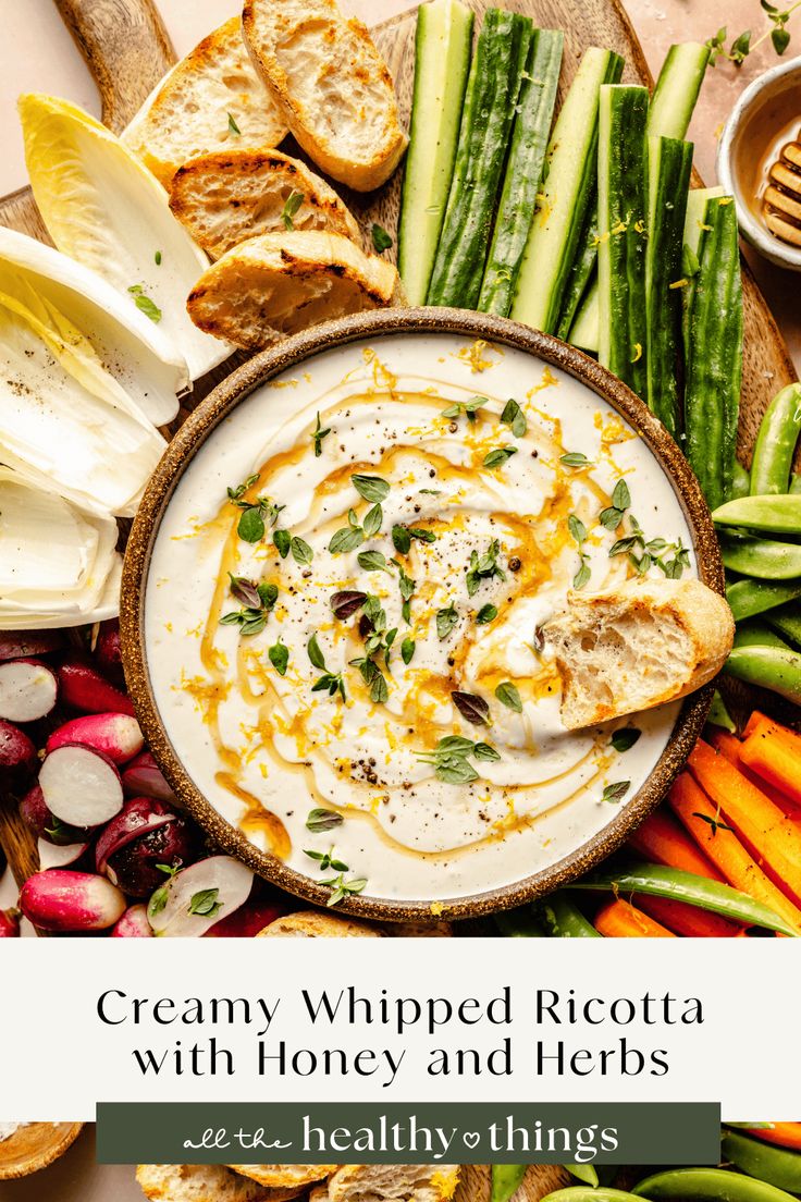 creamy whipped ricotta with honey and herbs on a platter surrounded by fresh vegetables