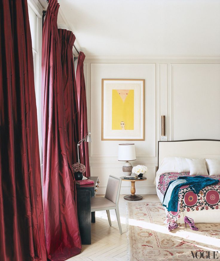 a bedroom with white walls and red curtains