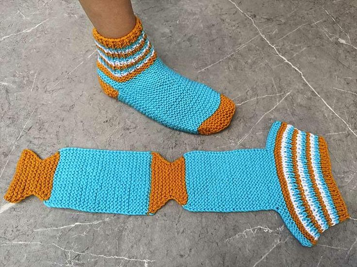 a person wearing blue and orange knitted socks with fish tails on the bottom of them