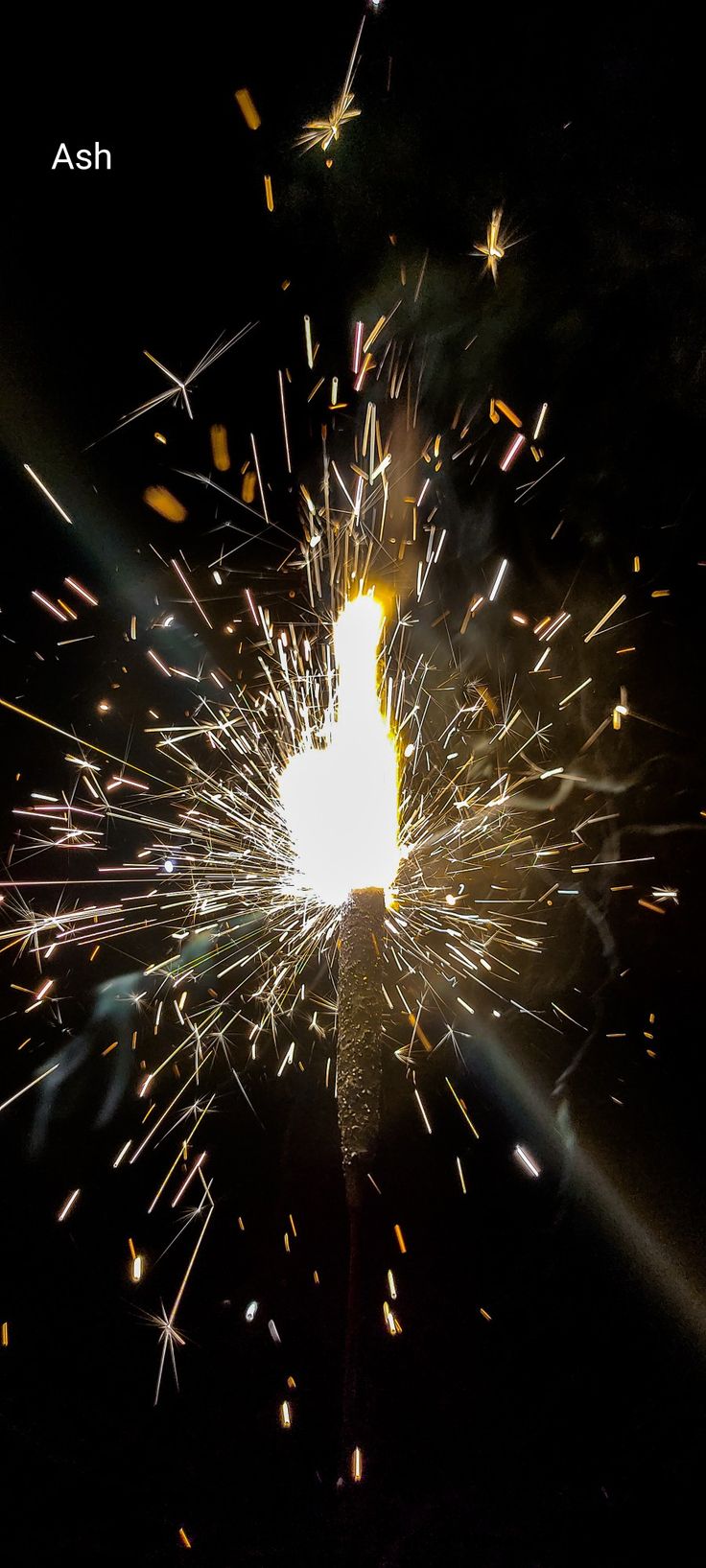 a sparkler is lit up in the dark with yellow and white stars around it