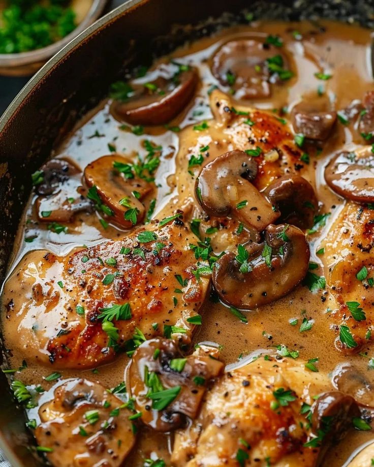 a pan filled with chicken and mushrooms covered in gravy