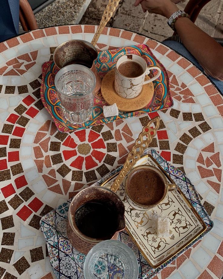 two cups of coffee sit on a mosaic table