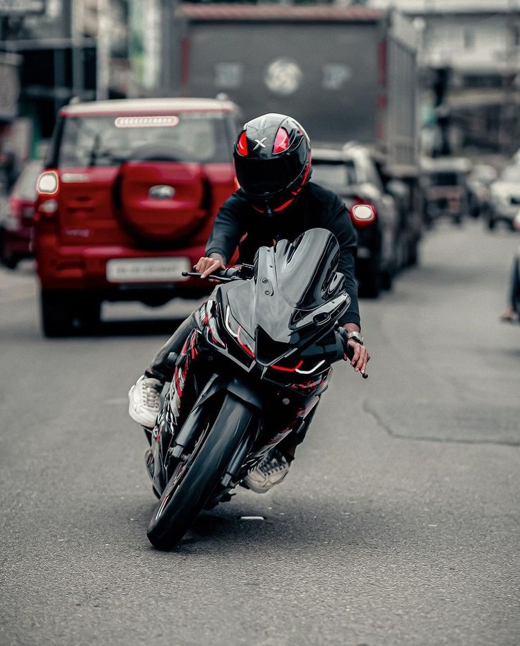 a man riding a motorcycle down the middle of a street next to cars and trucks