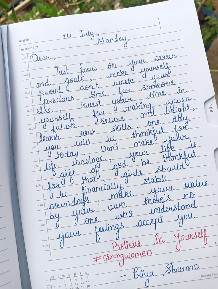 an open notebook with writing on it in blue and red ink next to a plant