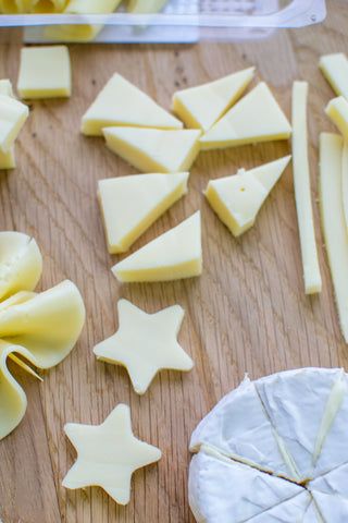 several pieces of cheese are cut up on a cutting board and ready to be eaten