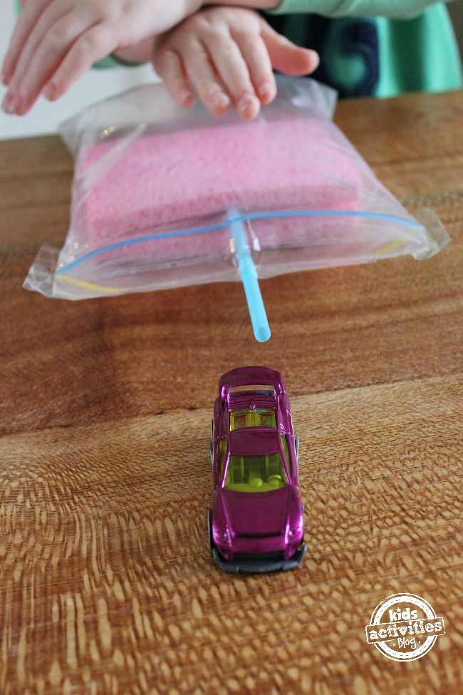 a small toy car sitting on top of a wooden table next to a plastic bag