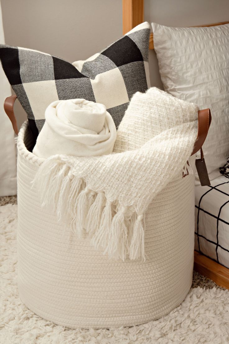 a white blanket sitting on top of a bed next to a pillow and throw pillows