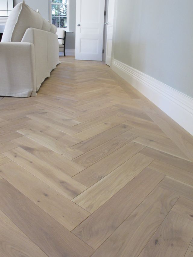 an empty living room with white furniture and wood flooring